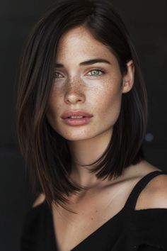 Portrait of a young woman with freckles, shoulder-length dark hair, and green eyes, gazing into the camera against a dark background. Light Brown Hair With Freckles, Cooler Brown Hair, Cool Toned Brunette Hair Color, Hair Color Ideas For Dark Skin Tone, Straight Brown Hair Balayage, Cool Brown Hair Color Dark, Dark Hair Lob, Dark Lob