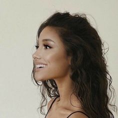 a close up of a woman with long hair and no bra smiling at the camera