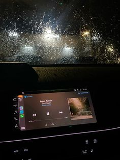 the dashboard of a car is covered in rain and ice as it drives down a street at night