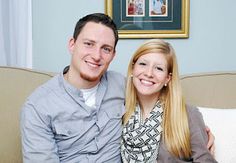 a man and woman are sitting on a couch smiling at the camera while posing for a photo