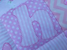 a pink and white quilt with the letter h on it