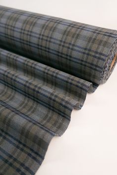 a roll of blue and grey plaid fabric on a white surface with the end rolled up