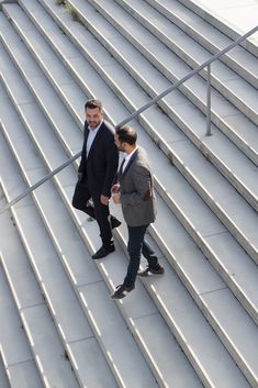 two men in suits walking up some steps