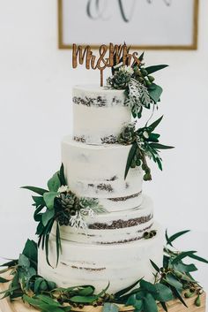 a white wedding cake with greenery on top