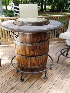 a wooden barrel table sitting on top of a wooden deck next to a white chair