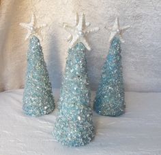 three small blue trees with white stars on them and one is made out of glitter