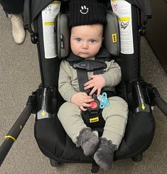 a baby sitting in a stroller wearing a hat