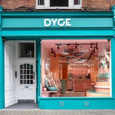 the storefront of dyge is painted teal and has many chairs in it