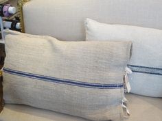 two pillows sitting on top of a white couch next to a shelf with wine bottles