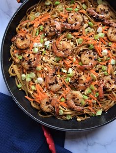 a pan filled with noodles and shrimp on top of a table