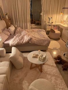 a bedroom with white furniture and lots of pillows on the bed, along with a small coffee table