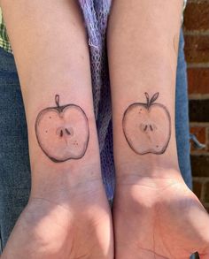 two people with matching tattoos on their wrists, one has an apple and the other has a skull