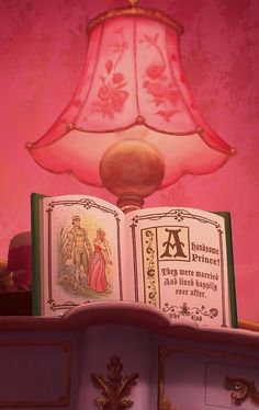 an illuminated lamp and book on top of a shelf in a room with pink walls