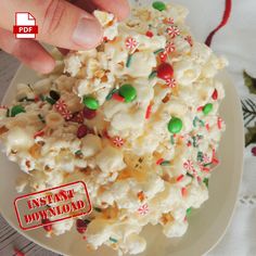 a hand is picking up popcorn from a white plate with candy canes and candies