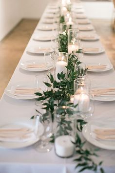 a long table is set with candles and greenery for an elegant dinner or party