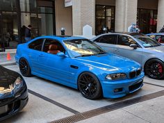 two blue cars parked next to each other in front of a building