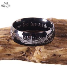 a ring with arabic writing on it sitting on top of a piece of driftwood