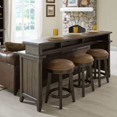 a dining table with four stools in front of it and a stone fire place