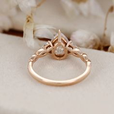 a close up of a ring on a white cloth with flowers in the back ground