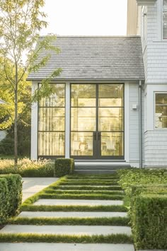 a white house with hedges in front of it and a walkway leading up to the door