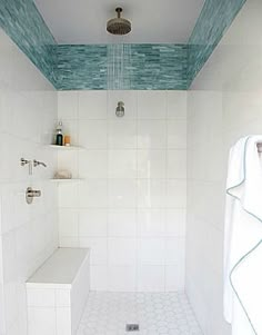 a white tiled bathroom with blue trim on the ceiling and shower head in the corner