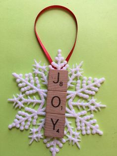 a snowflake ornament with the word joy spelled in wood block letters