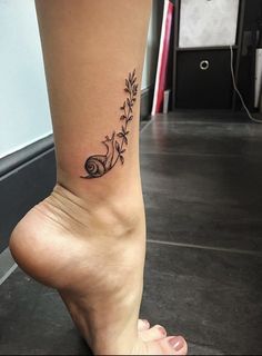 a woman's foot with a flower tattoo on the side of her leg,