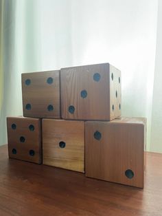 four wooden dices stacked on top of each other in front of a window with curtains