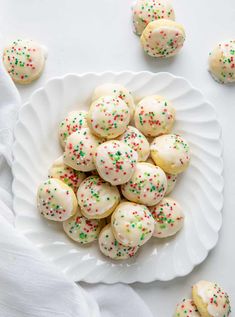 white plate filled with sprinkle covered cookies on top of a white tablecloth