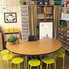 a classroom with several tables and chairs in the room, including two desks that have yellow stools on them