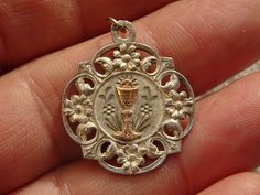 Religious antique silver ( MARKED ) French medal pendant charm medallion of Holy Chalice of the Holy Communion. Measures : 0,99 x 1,16 inches ( 2,52 x 2,95 cm ) The eye is on the place of the silver mark broken. Please look at all of the pictures, as they complete the description. I have a lot of these medals. I bought this medal on a brocante ( fleamarket in France). If you don't have paypal, you can pay by bank transfer. I deliver all over the world. Registered shipping is possible. If you wan Antique Silver Jewelry With Miraculous Medal, Antique Silver Medallion With Miraculous Medal, Antique Miraculous Medal Pendant Jewelry, Collectible Silver Engraved Charms, Vintage Medallion Charms As Gift, Vintage Medallion Charms As Gifts, Silver Engraved Charms For Collectors, Vintage Silver Jewelry With Miraculous Medal, Antique Charms Jewelry For Commemoration