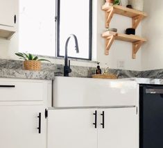 a kitchen with white cabinets and black appliances