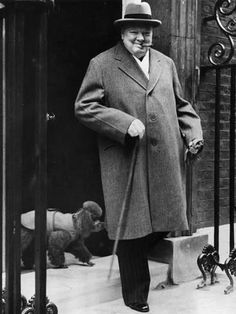 an old photo of a man in a coat and hat standing on the steps with his dog