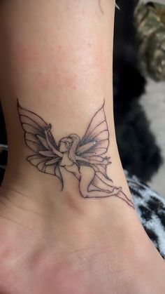 a small tattoo on the ankle of a woman's foot, depicting a fairy