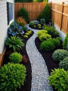 a small garden with rocks and plants in the center, along side a fenced yard