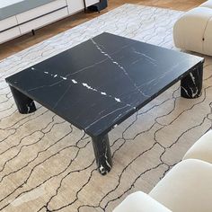 a black marble coffee table sitting on top of a rug