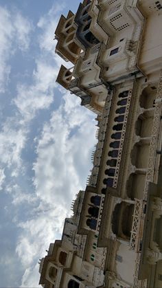 an ornate building with many windows and balconies on the sides against a cloudy blue sky