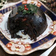 a piece of chocolate cake on a plate with christmas decorations and holly decoration around it