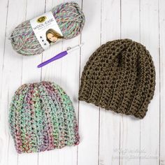 two crocheted hats are sitting next to each other on a white wooden surface