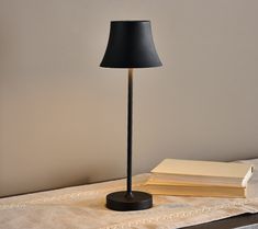 a black lamp sitting on top of a table next to a book