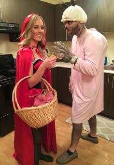 a man and woman in costumes standing next to each other on a kitchen floor, one holding a basket