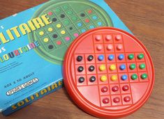 an orange board game sitting on top of a wooden table next to a blue box