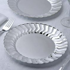 two white plates sitting on top of a table next to silverware and utensils