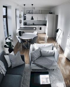 a living room filled with furniture next to a kitchen and dining room table on top of a hard wood floor