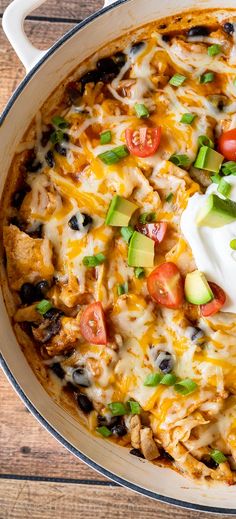 a casserole dish with chicken, black beans, avocado and sour cream