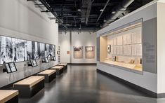 an empty room with benches and pictures on the wall in it's center area