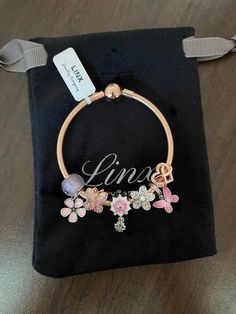 a personalized bracelet with flowers and butterflies is on display in a black velvet pouch