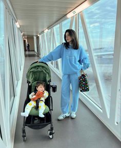 a woman standing next to a baby in a stroller