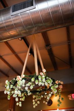 a chandelier with flowers hanging from it's sides in a room filled with wooden beams