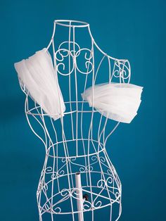 a white wire mannequin with two pieces of tulle on it's back